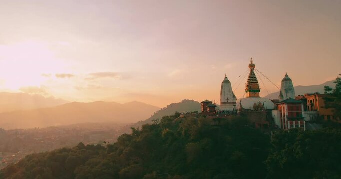 Gliding towards the Monkey Temple as the sun sets, our drone captures the majestic Swayambhunath Stupa in all its golden glory, a stunning sight amidst the peaceful landscape of Nepal.