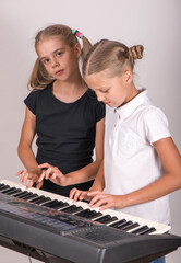 Two girls playing piano. Kids play music. Classical education for children. art lesson. Little girl at digital keyboard. Instrument for young student. Music class in school or at home.