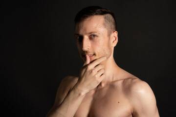 Fototapeta premium Young attractive man with an athletic body on a black background.