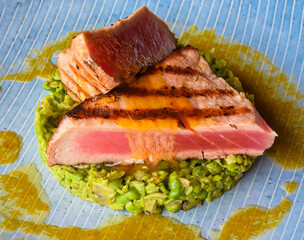 Tuna steak medium rare  served with peas isolated on black background side view
