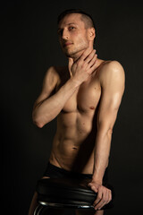 Fototapeta premium Young attractive man with an athletic body on a black background.