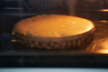 Process of preparing a turkey pie in a disposable paper baking dish. Pie with poultry meat being cooked in the oven in the home kitchen