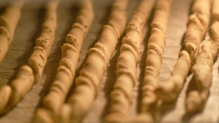 Process of cooking bread strips on disposable baking paper. Grissini breadsticks are cooked in the oven in the home kitchen