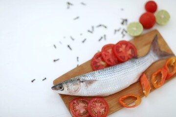 Brown fish, one fish on a white table, sliced ​​tomatoes, chili pepper, healthy food, very useful product, contains protein, easily digestible, omega-3 fatty acids, method of preparation, background, 