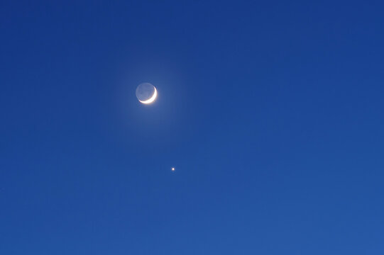 Venus next to the moon in the night starry sky. The new moon and the planet Venus move across the sky from evening to night