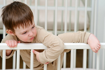 Baby escapes from the crib by climbing over the bars. The child climbs over the railing bed. Kid...
