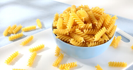 Raw Italian pasta fusilli. traditional italian food close up. uncooked pasta on a light background. yellow noodles. mediterranean cuisine.
