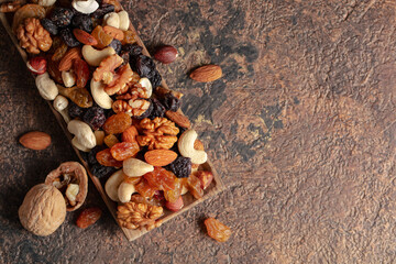 Mix of nuts and raisins on a brown rustic background.