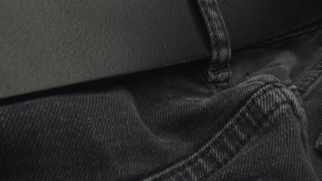 Black leather belt in black jeans of man pants, dolly backward