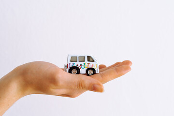Woman's hand holding minibus toy car