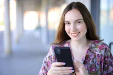 Happy woman holding cellphone looking at camera