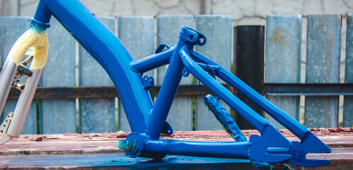 a man paints a bicycle with spray paint.