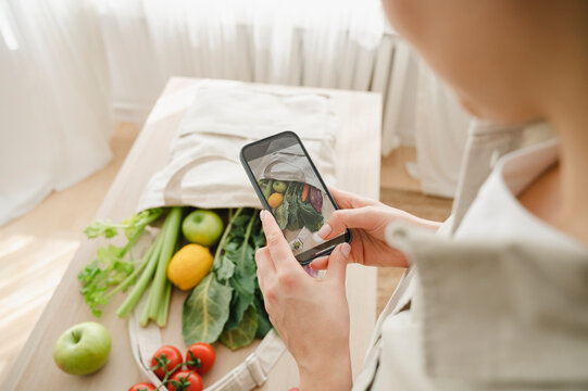 Woman photographing groceries through smart phone at home