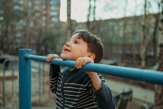 Smiling boy playing on monkey bar at park