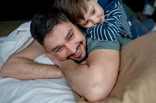 Happy man lying with son on bed at home