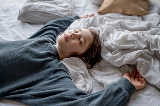 Carefree boy sleeping on bed at home