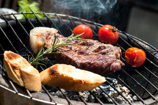 Meat, tomatoes and baguette slices cooking on barbecue grill