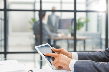 Image of human hands during discussion of paper and electronic documents at meeting.