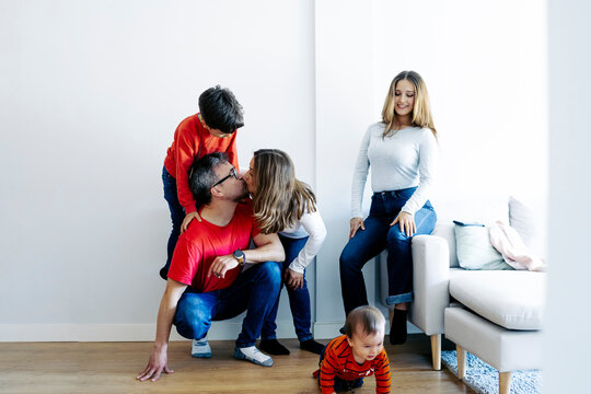 Father and mother kissing by children playing at home