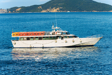 White empty tourist ferry to the Cinque Terre (tour boat) in front of the ancient village of Tellaro, Mediterranean sea, Gulf of La Spezia, Liguria, Italy, Europe. On background the Palmaria island.