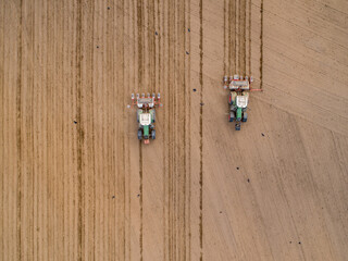 Harvester, tractor plowing land in Poland, preparing for sowing - agriculture drone aerial photo from above