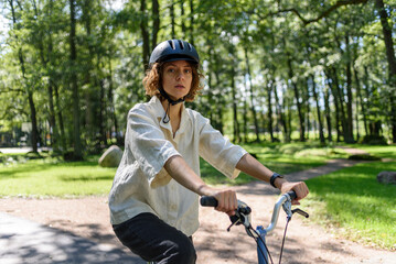 Fototapeta na wymiar Woman in helmet riding on bicycle at city public park