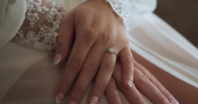 close up shot of bride's hands with her wedding ring in slow motion in her wedding gown