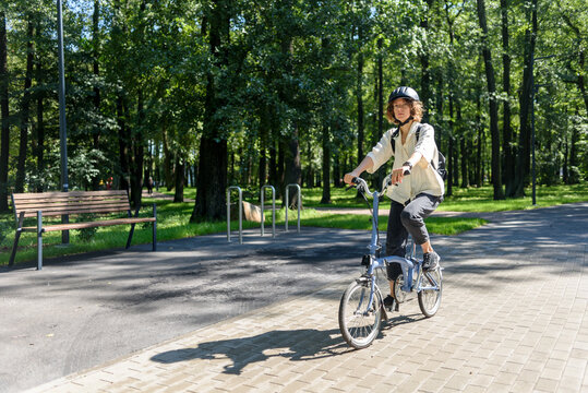 Woman in helmet riding on bicycle at city public park