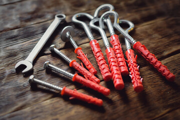 Concrete nails, hook and wrench on the wooden workbench background close up.