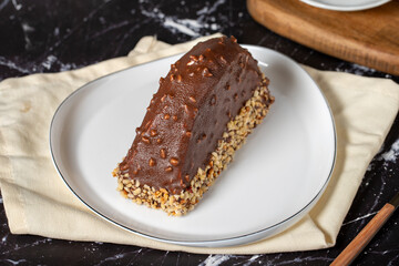 Banana and chocolate cream cake. Chocolate covered and hazelnut malaga cake on a dark background.