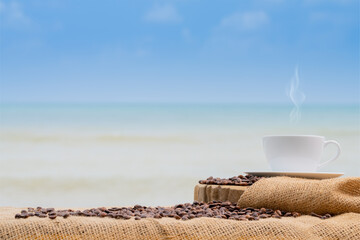 Fototapeta na wymiar Close-up white coffee cup and many coffee beans placed around on the wood table with a beautiful seascape of nature background, concept coffee vacation travel.