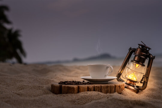 Close-up white coffee cup and many coffee beans placed around on the wood table with a beautiful seascape of nature background, concept coffee vacation travel, beautiful morning light background.