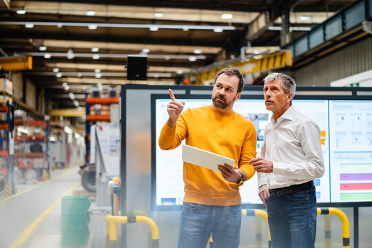 Businessman explaining and having discussion with colleague in factory
