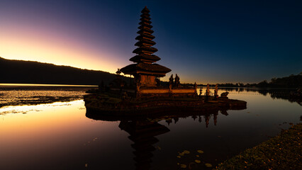 Hindu water temple in Bali, Pura Ulun Danu Bratan, features pagodas, gardens, lotus ponds, set against a backdrop of mist-shrouded mountains on Lake Bratan © mhong84