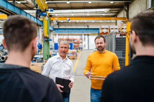 Businessman and manager communicating with employees at factory