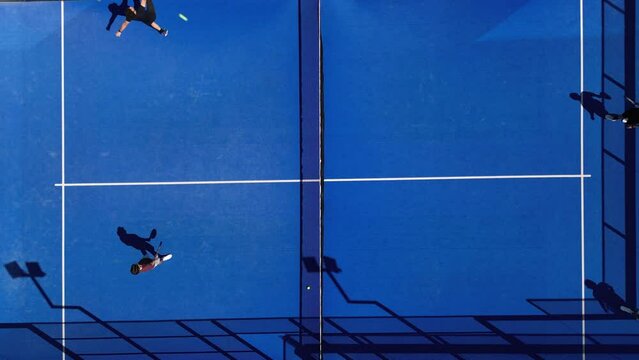 Aerial top view shot of padel tennis players playing on the court in summer.