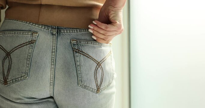 Woman pulling out condom from jeans pocket closeup. Safe sex concept
