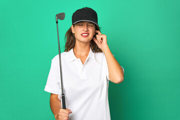 Young caucasian golfer holding a golf stick isolated Young caucasian golcovering ears with hands.