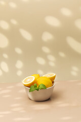 Still life yellow ripe lemons in a ceramic plate with a sprig of mint on the table. Copy space