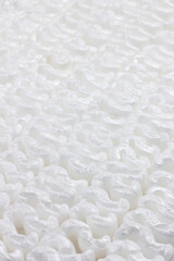 Texture formed by the regular repetition of wavy white polystyrene pieces.