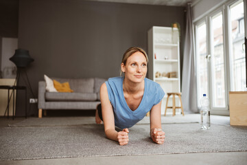 Young blonde woman practicing yoga in her apartment