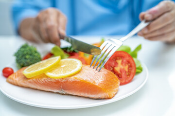 Asian elderly woman patient eating salmon steak breakfast with vegetable healthy food in hospital.