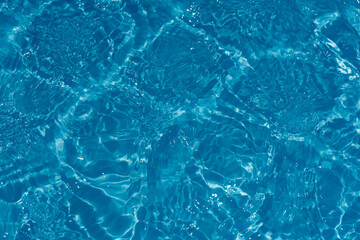 Blue water with ripples on the surface. Defocus blurred transparent blue colored clear calm water surface texture with splashes and bubbles. Water waves with shining pattern texture background.