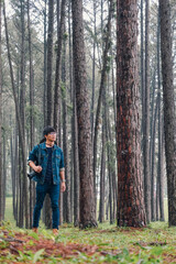 Fototapeta premium Traveler woman take a photograph in nature Pine Park. Tourist with camera travel photo of photographer Making pictures Traveling Trip Sightseeing Tourism concept.