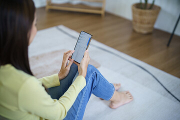Asian Woman with Smartphone on sofa working mobile devices. cell telephone technology e-commerce concept. Relax at hom