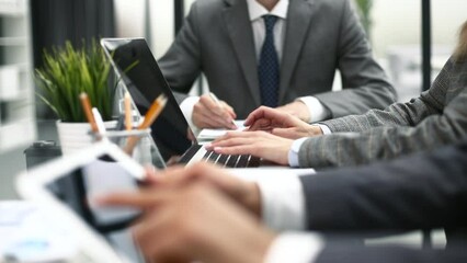Business professionals working together at office desk, analyzing financial statistics displayed on the laptop screen.
