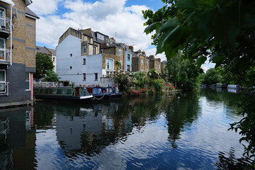 Fototapeta na wymiar London - 05 21 2022: Boats moored on the Grand Union Canal near houses on Hormead Rd