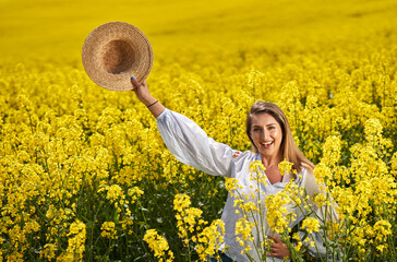 Fototapeta premium Beautiful blonde latino woman in a canola field