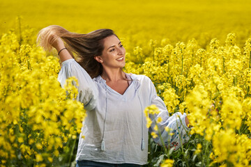 Fototapeta premium Beautiful blonde latino woman in a canola field