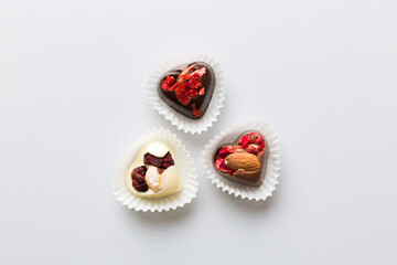 chocolate sweets in the form of a heart with fruits and nuts on a colored background. top view with space for text, holiday concept